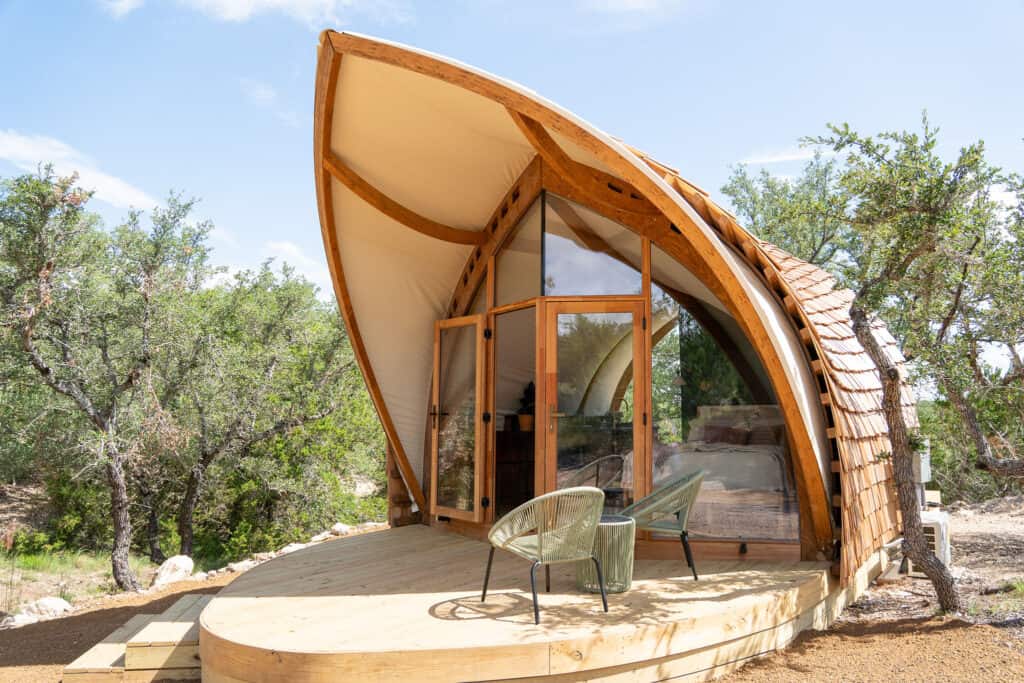 Contemporary dome-shaped eco-friendly wooden tiny house with large glass windows and a spacious wooden deck, surrounded by natural desert landscape, perfect for outdoor living, camping, and sustainable retreats.