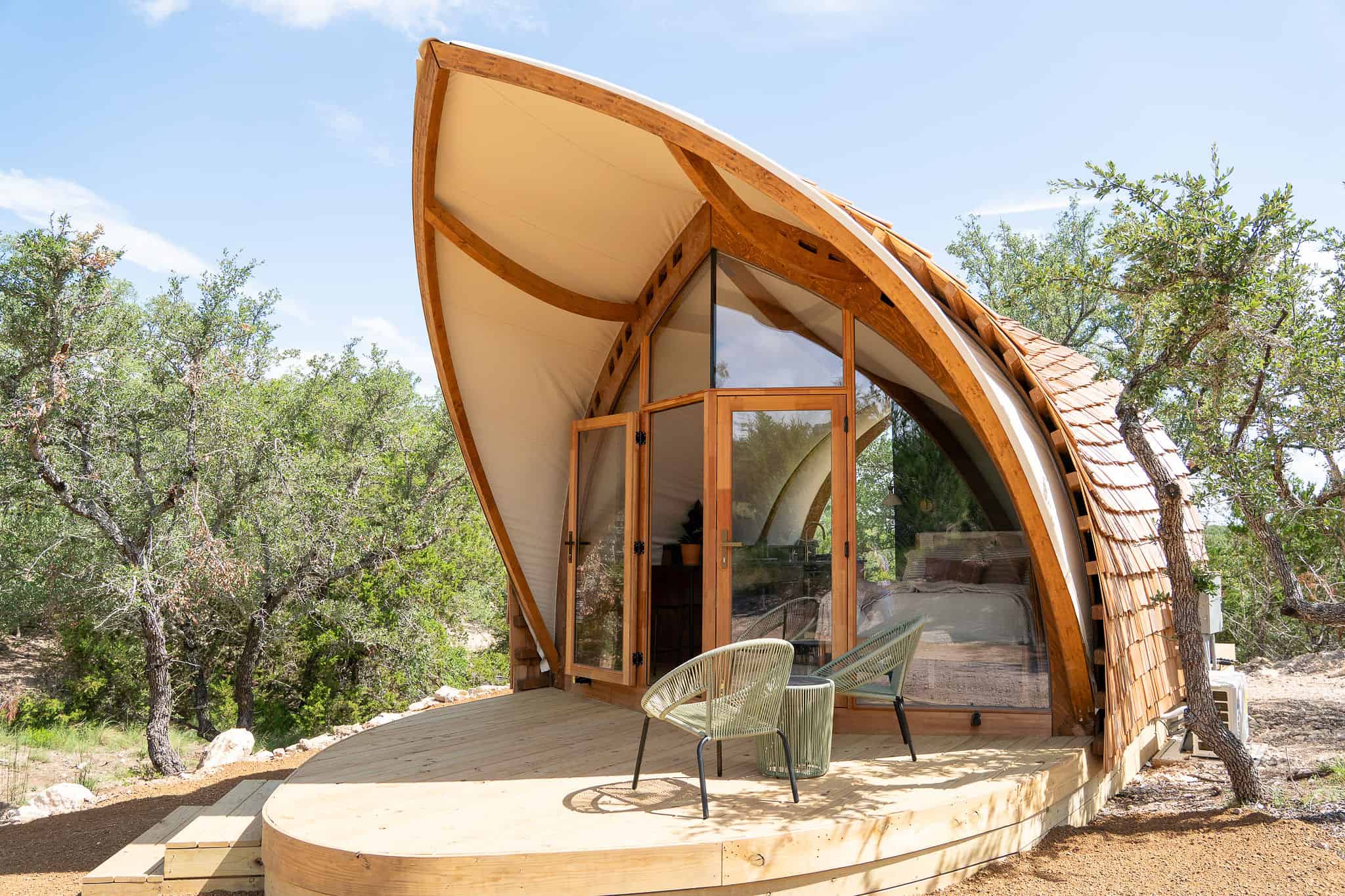 Contemporary dome-shaped eco-friendly wooden tiny house with large glass windows and a spacious wooden deck, surrounded by natural desert landscape, perfect for outdoor living, camping, and sustainable retreats.