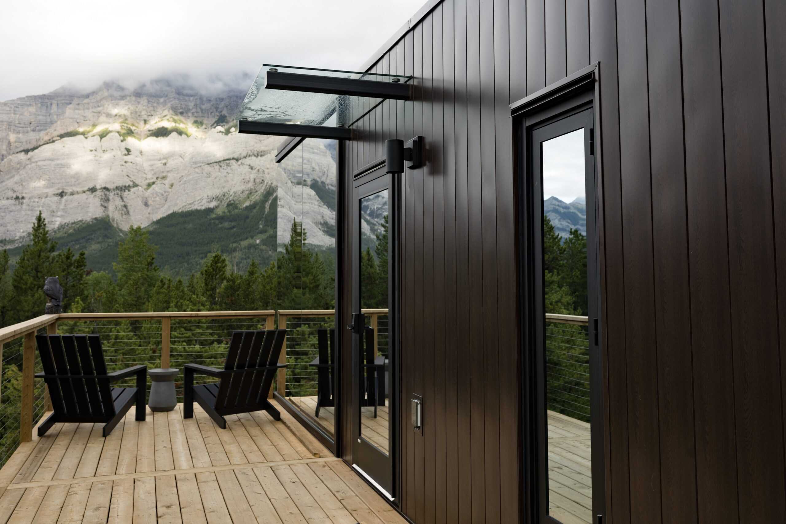 Modern mountain cabin porch with wood decking, outdoor seating, and stunning mountain view, designed for outdoor relaxation and nature connection, ideal for outdoor living enthusiasts.
